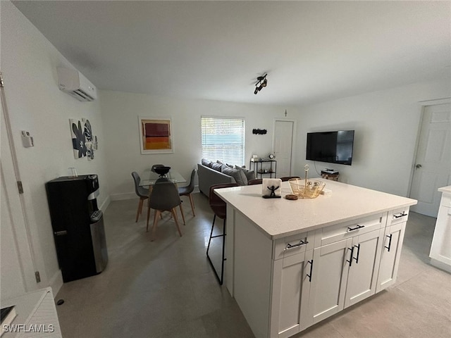 kitchen featuring white cabinets, a wall unit AC, a breakfast bar, and a center island