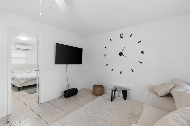 living area with a wall unit AC, light tile patterned floors, baseboards, and a ceiling fan