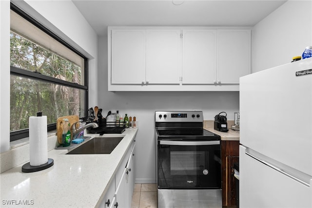 kitchen featuring stainless steel electric range, white fridge, light tile patterned floors, sink, and white cabinets