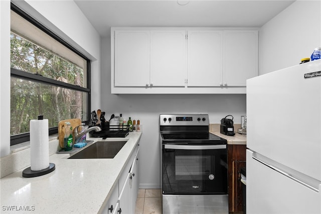 kitchen with freestanding refrigerator, electric stove, a sink, and white cabinetry