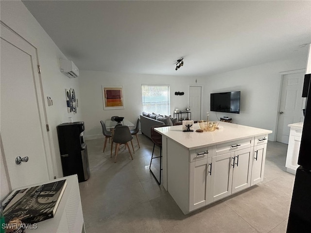 kitchen with white cabinets, a wall unit AC, a kitchen breakfast bar, and a center island