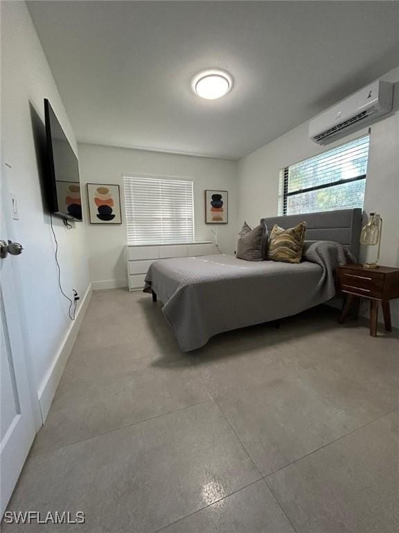 bedroom featuring a wall mounted air conditioner, concrete flooring, and baseboards