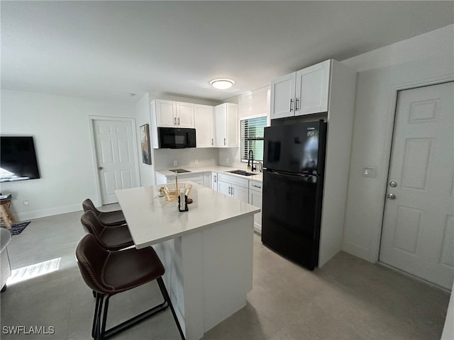 kitchen featuring black appliances, white cabinetry, a kitchen bar, sink, and a center island