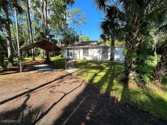 view of front of home with a detached carport, a front yard, and driveway