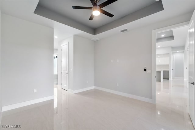 empty room with a tray ceiling and ceiling fan