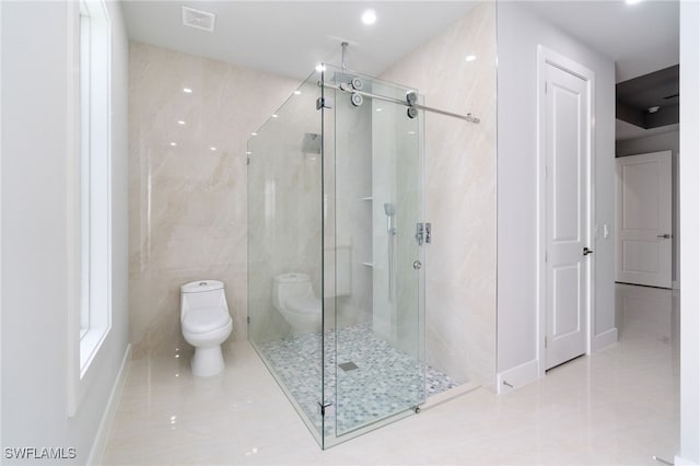 bathroom with tile patterned floors, toilet, tile walls, and a shower with shower door