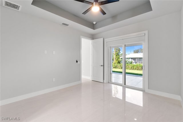 tiled spare room with a raised ceiling and ceiling fan