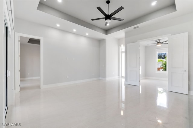 unfurnished room with ceiling fan and a tray ceiling