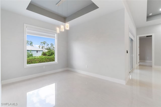 unfurnished room featuring a notable chandelier and a tray ceiling