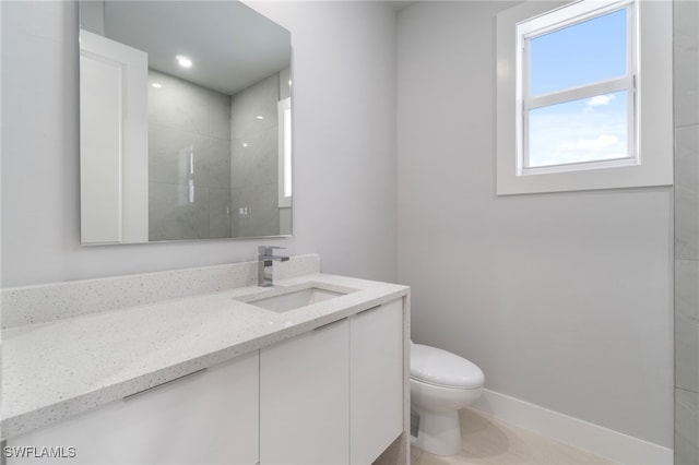 bathroom featuring tile patterned flooring, a tile shower, vanity, and toilet