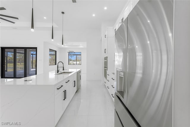 kitchen featuring white cabinetry, sink, light stone counters, decorative light fixtures, and appliances with stainless steel finishes