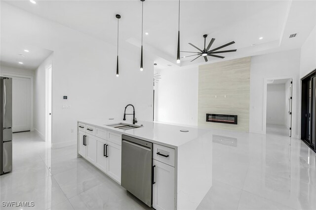 kitchen featuring stainless steel appliances, light countertops, white cabinetry, pendant lighting, and a sink