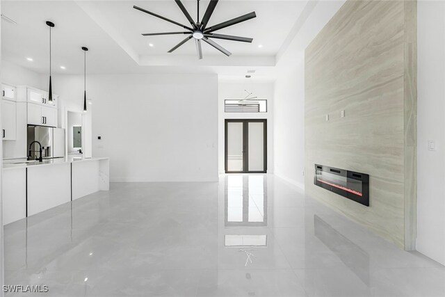 unfurnished living room featuring a tray ceiling and a large fireplace