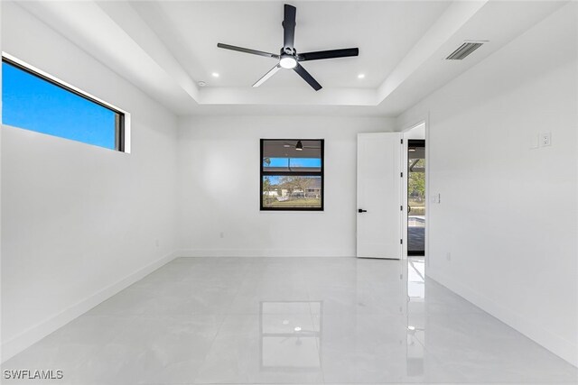 empty room featuring baseboards, visible vents, a tray ceiling, and recessed lighting