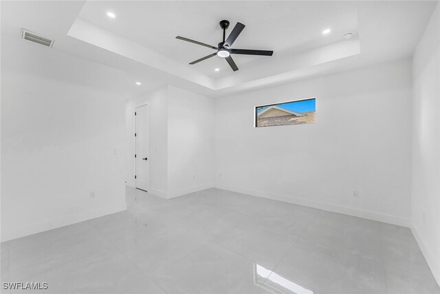 unfurnished room with a tray ceiling, visible vents, baseboards, and recessed lighting