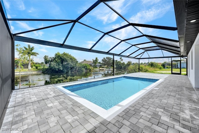 view of pool featuring glass enclosure, a patio area, and a water view