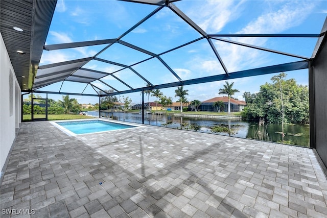 view of swimming pool with glass enclosure, a patio area, and a water view