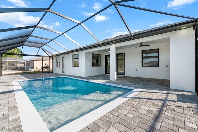 outdoor pool with a lanai, ceiling fan, and a patio