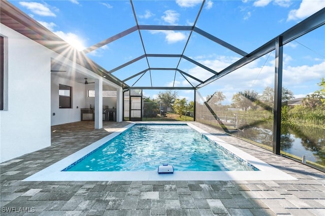 outdoor pool featuring a water view, glass enclosure, ceiling fan, and a patio area