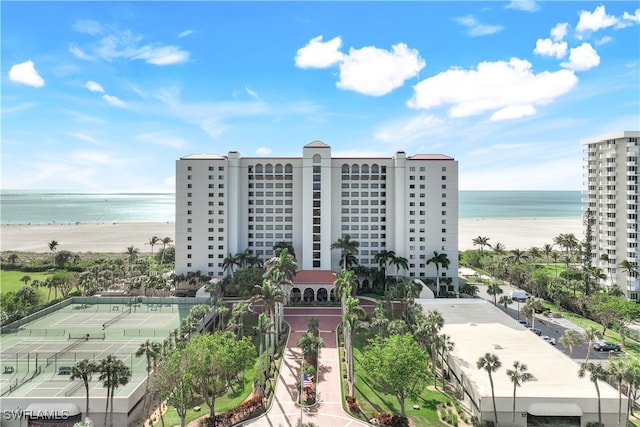 view of building exterior featuring a water view and a beach view