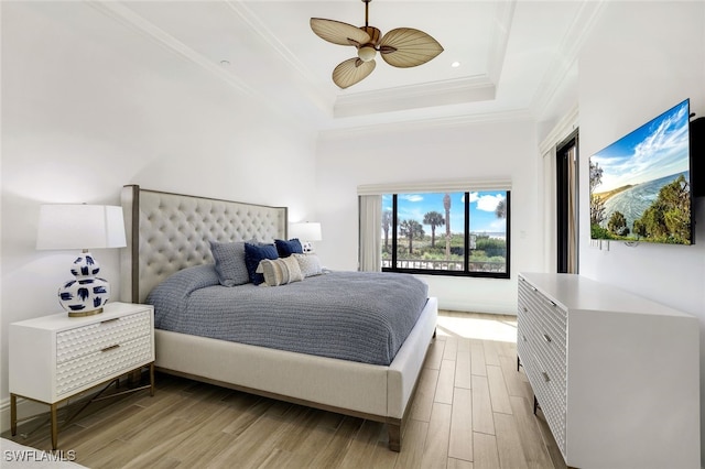 bedroom with ornamental molding, a raised ceiling, ceiling fan, and light hardwood / wood-style flooring