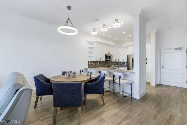 dining room featuring ornamental molding, light hardwood / wood-style flooring, and sink