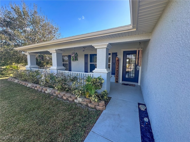 view of exterior entry with a yard and covered porch