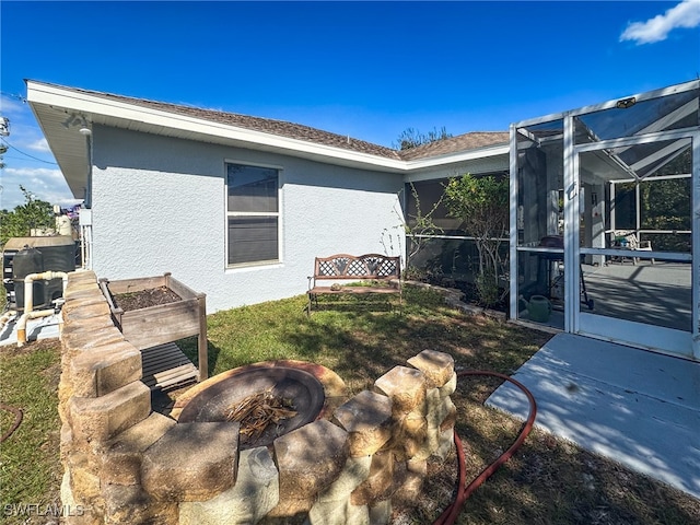 exterior space featuring glass enclosure, an outdoor fire pit, and a patio area