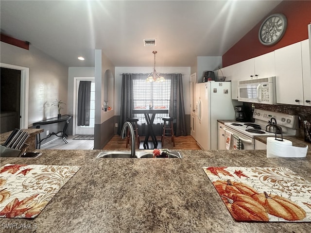 kitchen with sink, hanging light fixtures, white appliances, white cabinets, and vaulted ceiling