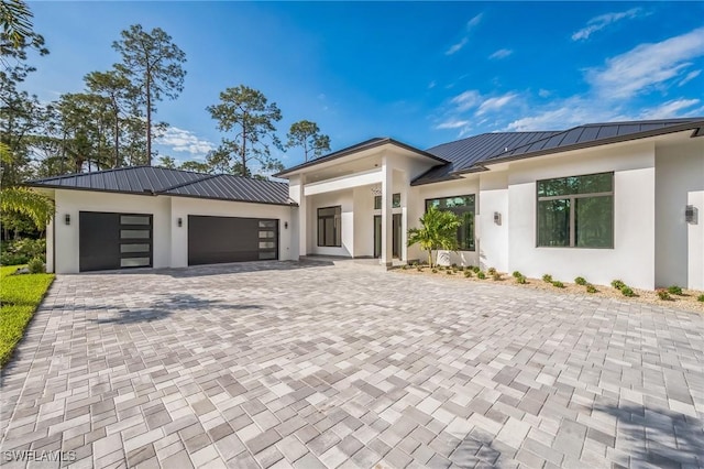 1125 Oakes Blvd, Naples, FL 34119 - contemporary home featuring stucco siding, a standing seam roof, an attached garage, metal roof, and decorative driveway