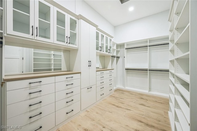 walk in closet with light hardwood / wood-style floors