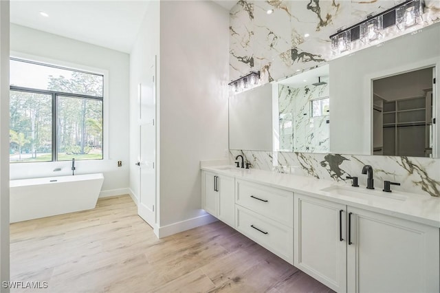 bathroom featuring tasteful backsplash, vanity, wood-type flooring, and shower with separate bathtub