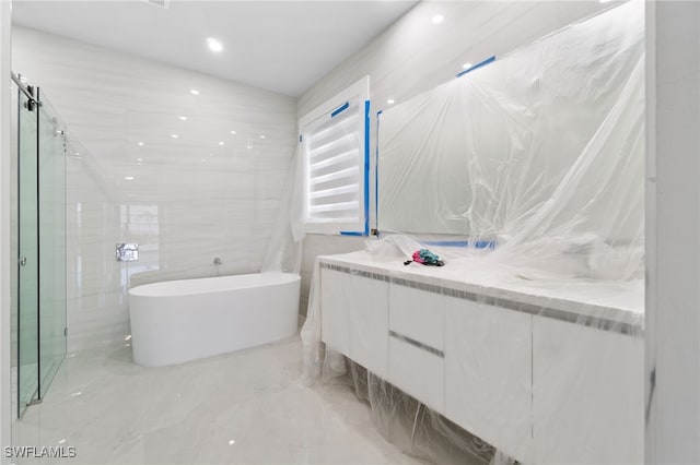 bathroom featuring vanity, separate shower and tub, and tile walls