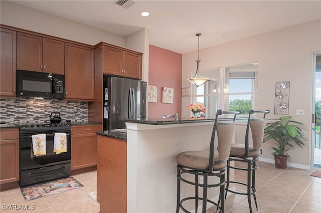 kitchen with a kitchen island, tasteful backsplash, dark stone counters, light tile patterned floors, and black appliances