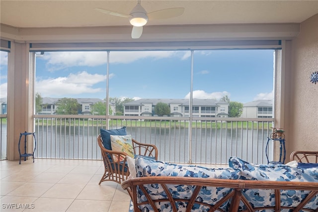 sunroom / solarium featuring ceiling fan and a water view