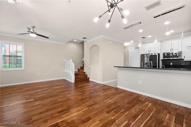 unfurnished living room with ceiling fan with notable chandelier, dark hardwood / wood-style flooring, and crown molding