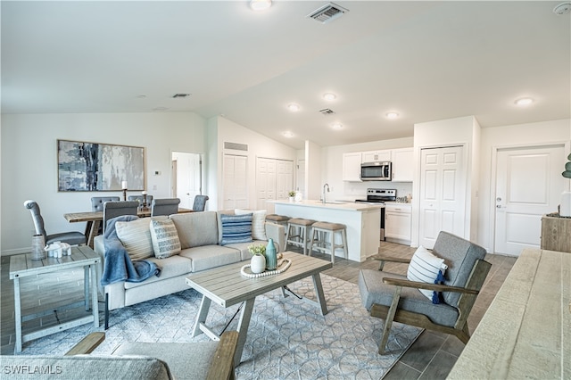 living room with hardwood / wood-style flooring, vaulted ceiling, and sink