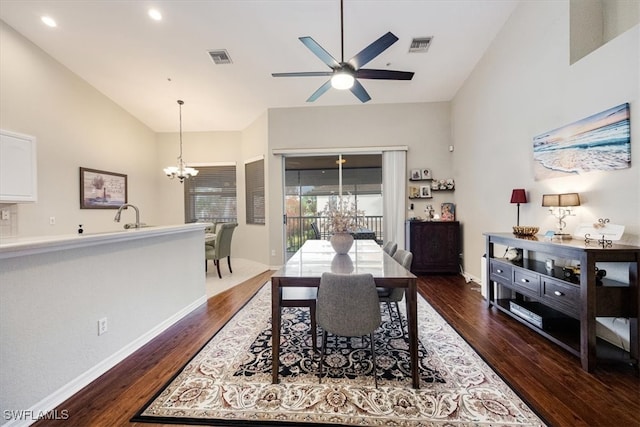 dining area featuring ceiling fan with notable chandelier, vaulted ceiling, dark wood-type flooring, and sink