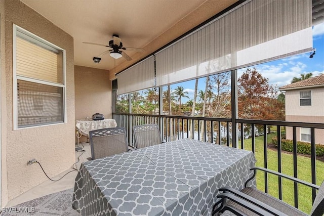 sunroom with ceiling fan and a water view