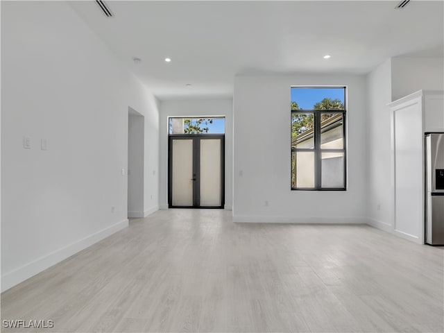 unfurnished living room with french doors and light hardwood / wood-style flooring