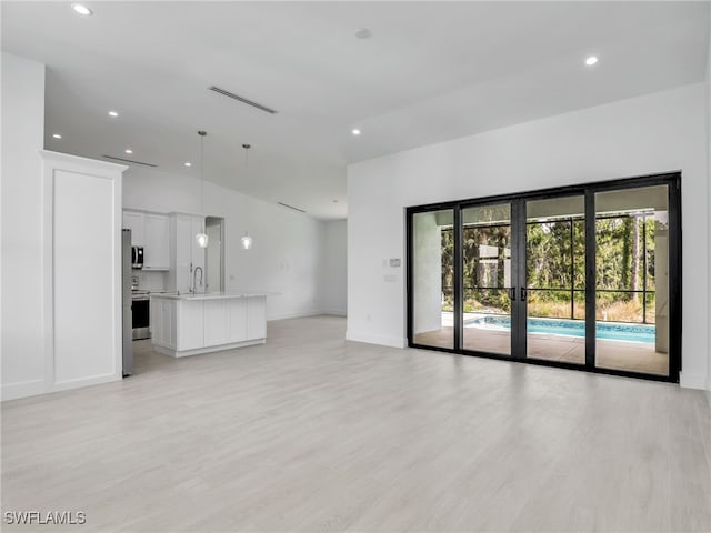 unfurnished living room featuring french doors, light hardwood / wood-style flooring, and sink