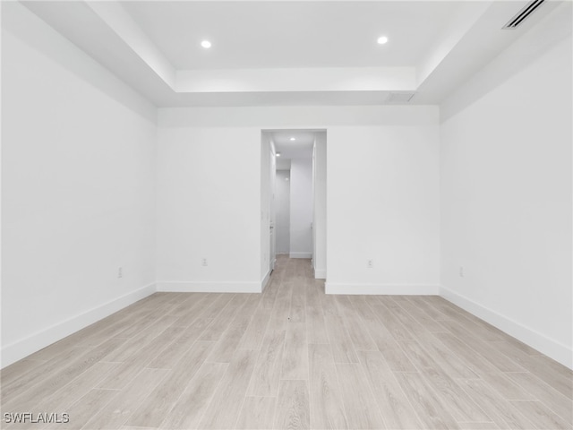 unfurnished room featuring a raised ceiling and light hardwood / wood-style flooring