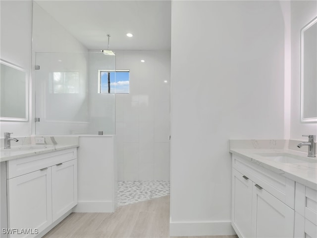 bathroom with wood-type flooring, vanity, and a tile shower