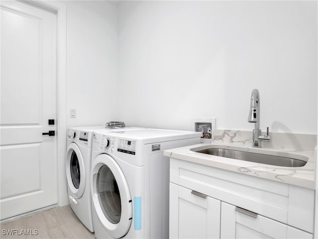 clothes washing area featuring washer and dryer, cabinets, and sink