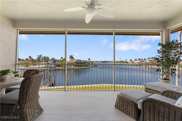 sunroom / solarium with ceiling fan and a water view