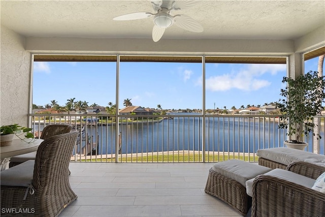 sunroom / solarium with a water view and ceiling fan