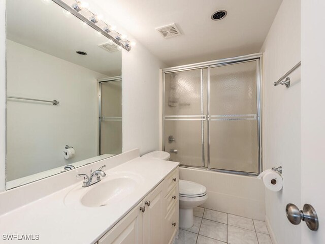 full bathroom with tile patterned flooring, vanity, combined bath / shower with glass door, and toilet