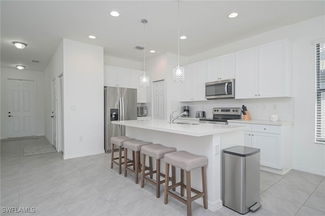 kitchen with white cabinets, a center island with sink, sink, and appliances with stainless steel finishes