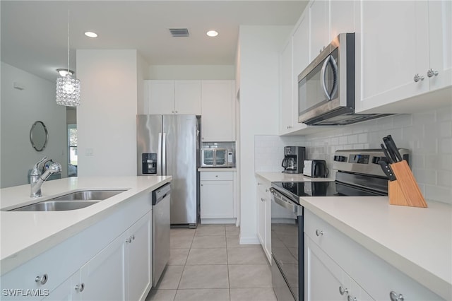 kitchen featuring sink, appliances with stainless steel finishes, light tile patterned floors, hanging light fixtures, and white cabinets