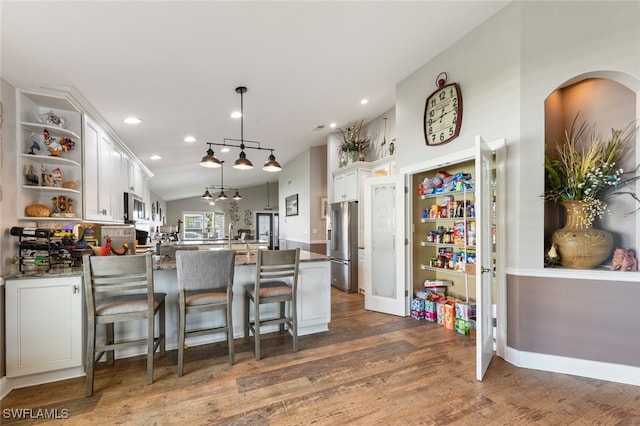 kitchen featuring a breakfast bar, decorative light fixtures, lofted ceiling, white cabinets, and dark wood-type flooring